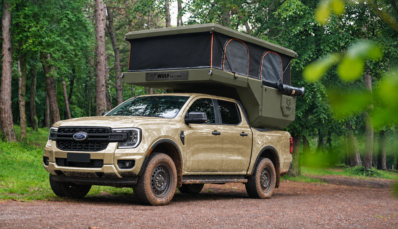 Front three-quarter view of a sand Ford Ranger with a tactical olive WOLF CAMPER pickup camper, roof raised on a forest track.