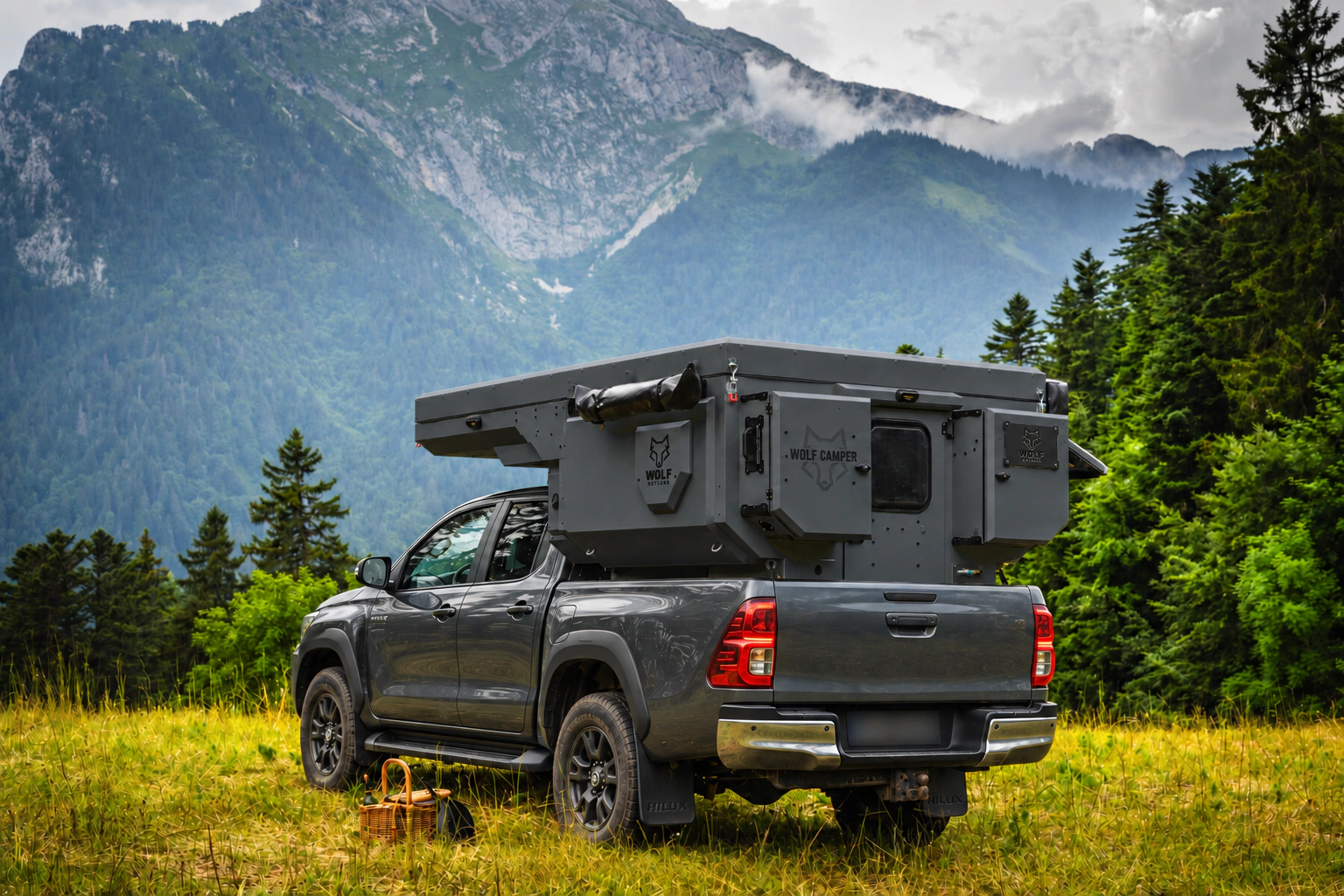 Toyota Hilux in anthracite grey with WOLF CAMPER in Graphite, solid cabinets — Rear left three-quarter, Roof closed, Black laser engraving.