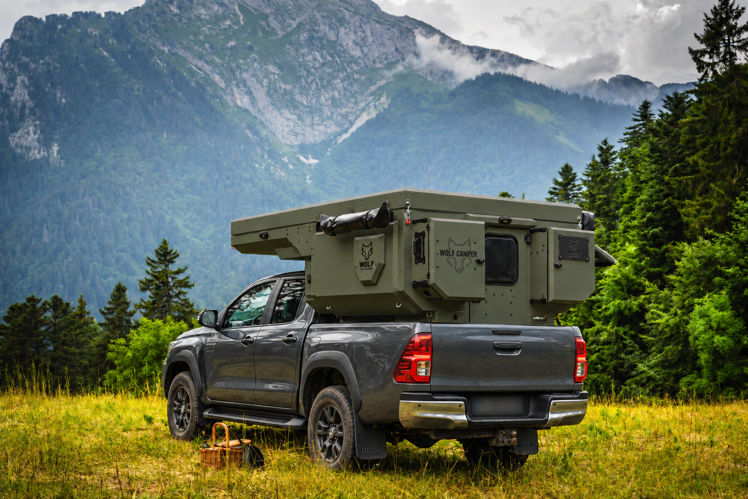 Toyota Hilux in anthracite grey with WOLF CAMPER in Tactical olive, solid cabinets — Rear left three-quarter, Roof closed, Black laser engraving.