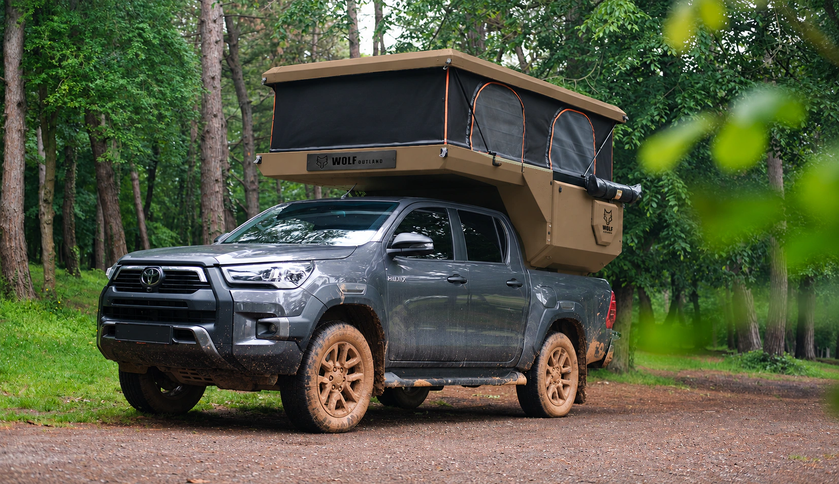 Toyota Hilux in anthracite grey with WOLF CAMPER in Bronze, solid cabinets — Front left three-quarter, Roof raised, Black laser engraving.