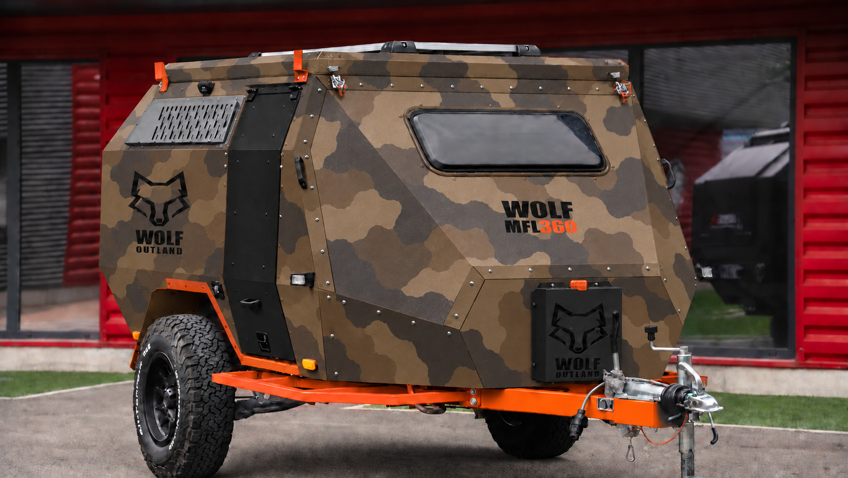 Front three-quarter view · right side of WOLF MFL 360 caravan in dark desert camouflage, roof closed · door closed. Front three-quarter view · right side of WOLF MFL 360 caravan in dark desert camouflage, roof closed · door closed.