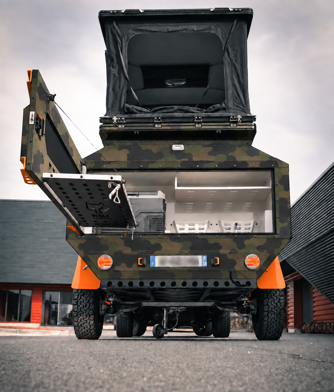 Rear view of WOLF Overland caravan in army camouflage, tent raised · storage open.