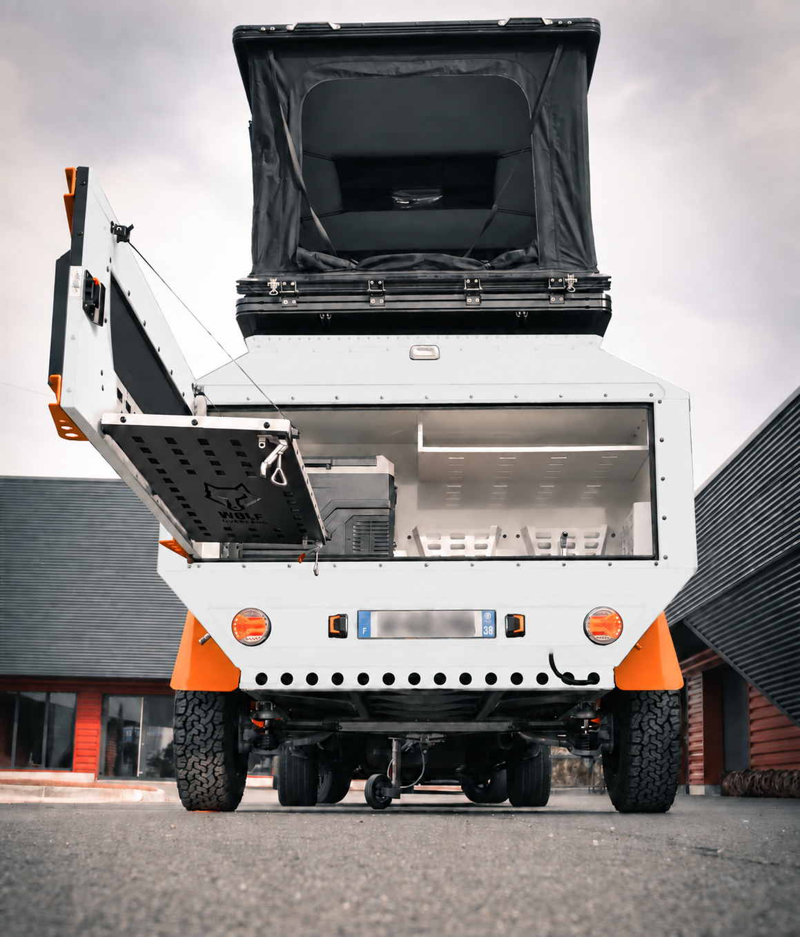Rear view of WOLF Overland caravan in glacier white, tent raised · storage open.