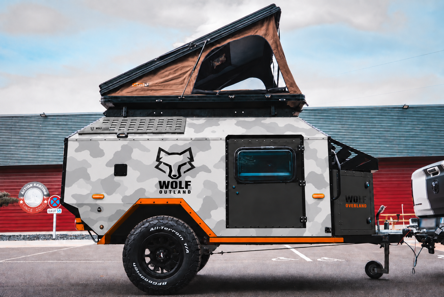 Side view of WOLF Overland caravan in light snow camouflage, tent raised · doors closed.