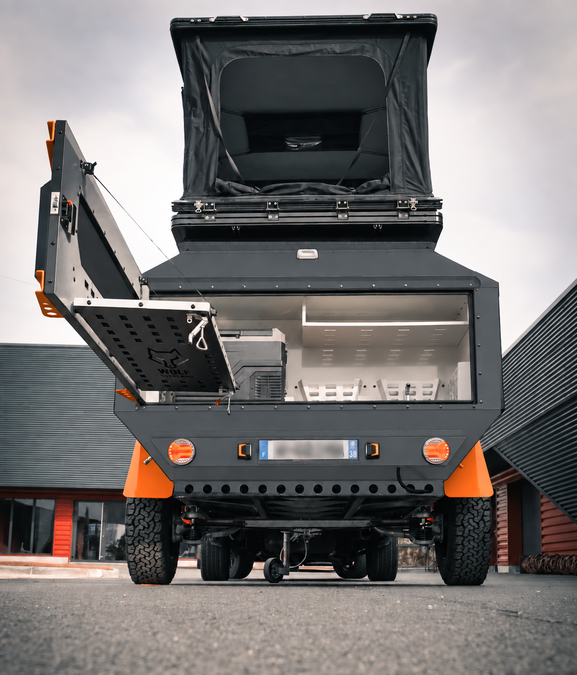 Rear view of WOLF Overland caravan in graphite, tent raised · storage open.