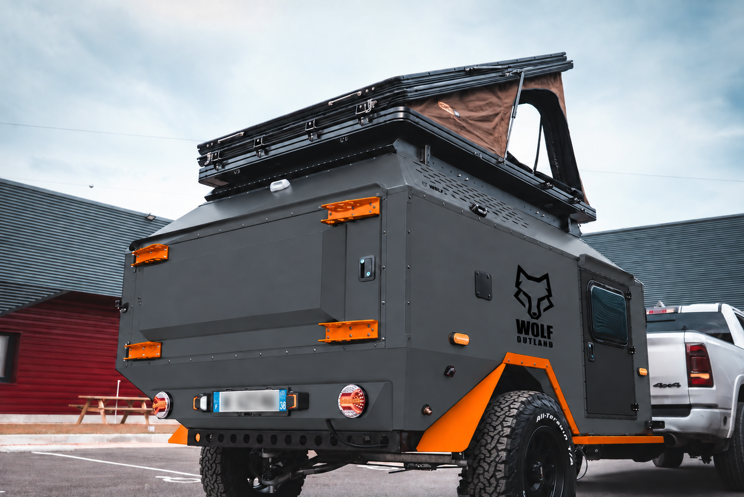 Rear three-quarter view of WOLF Overland caravan in graphite, tent raised · storage closed.