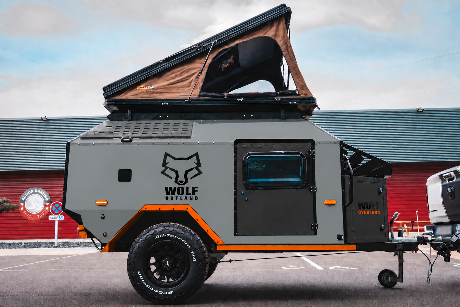 Side view of WOLF Overland caravan in mineral grey, tent raised · doors closed.