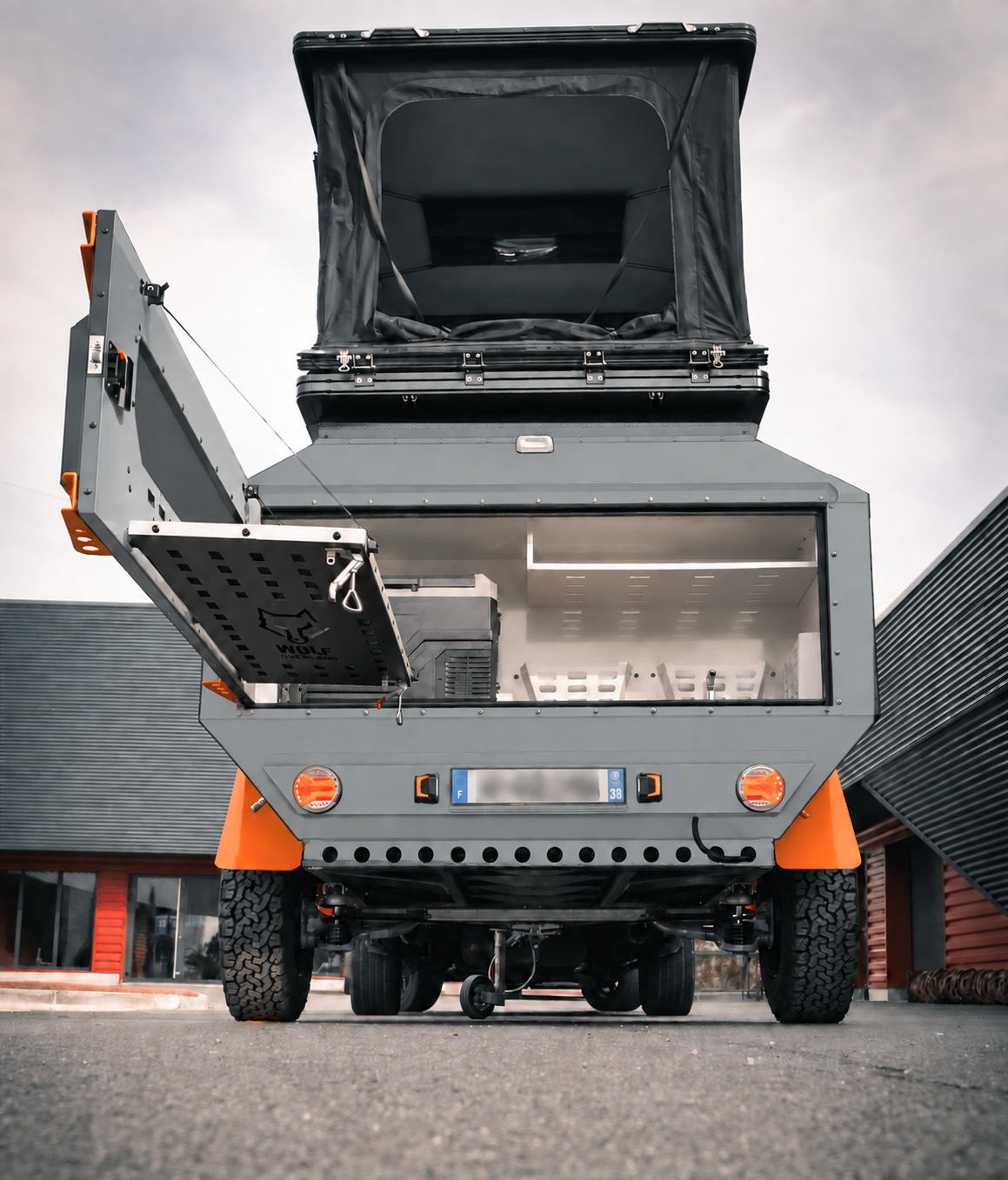 Rear view of WOLF Overland caravan in mineral grey, tent raised · storage open.