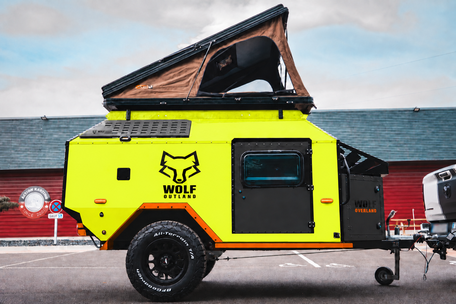 Side view of WOLF Overland caravan in fluorescent yellow, tent raised · doors closed. Side view of WOLF Overland caravan in fluorescent yellow, tent raised · doors closed.