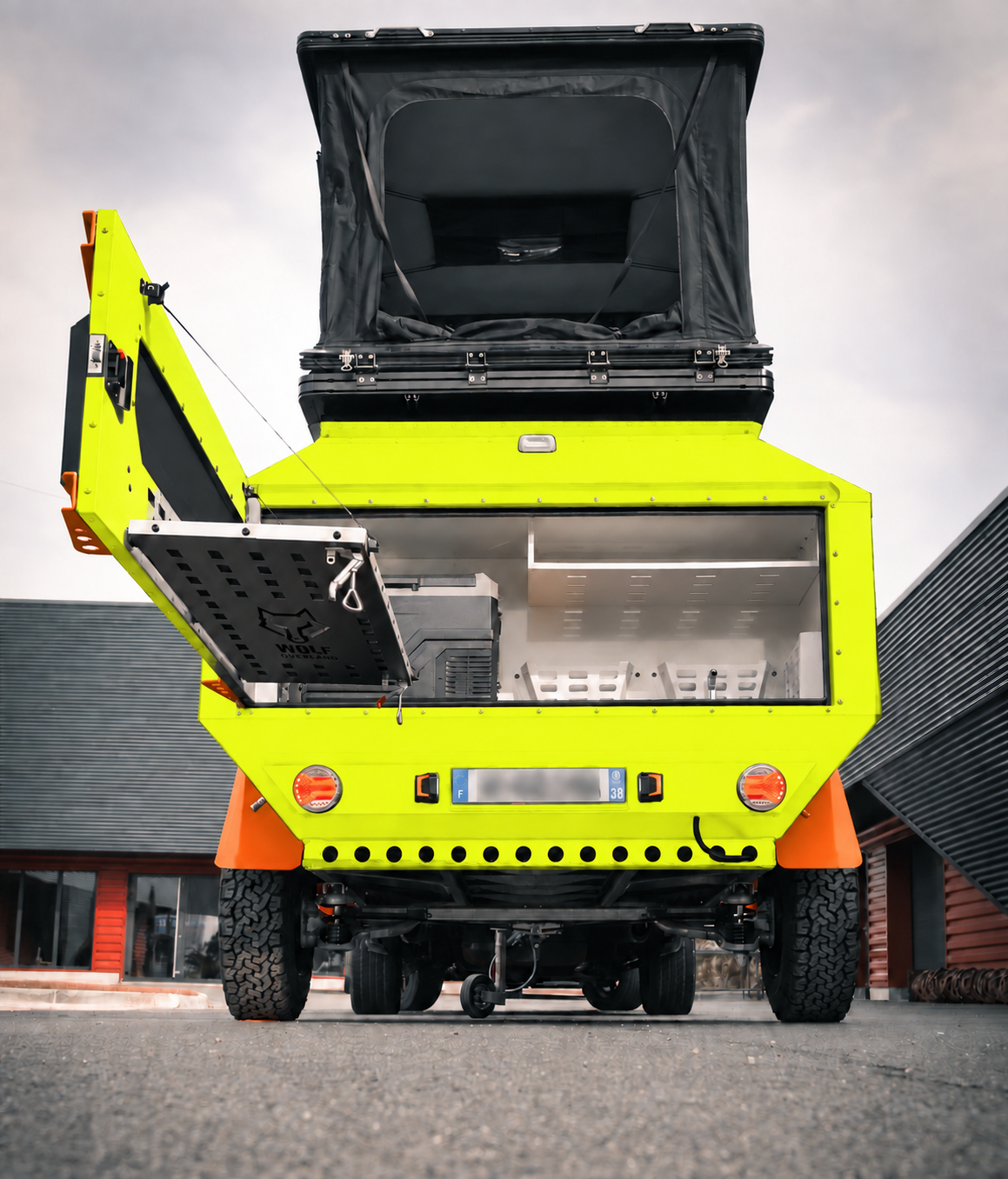Rear view of WOLF Overland caravan in fluorescent yellow, tent raised · storage open.