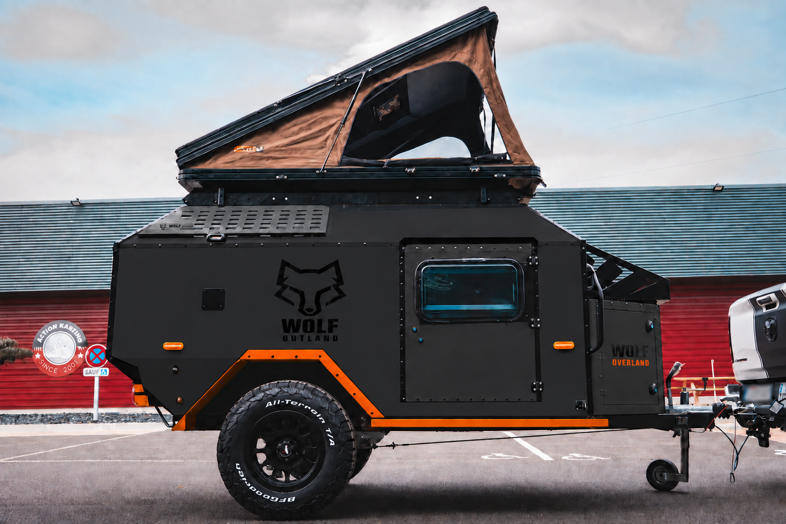 Side view of WOLF Overland caravan in matt black, tent raised · doors closed.