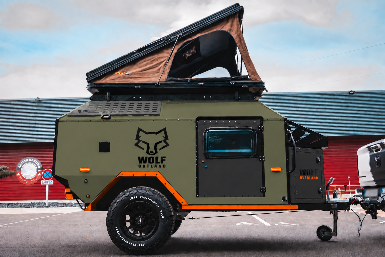 Side view of WOLF Overland caravan in tactical olive, tent raised · doors closed.