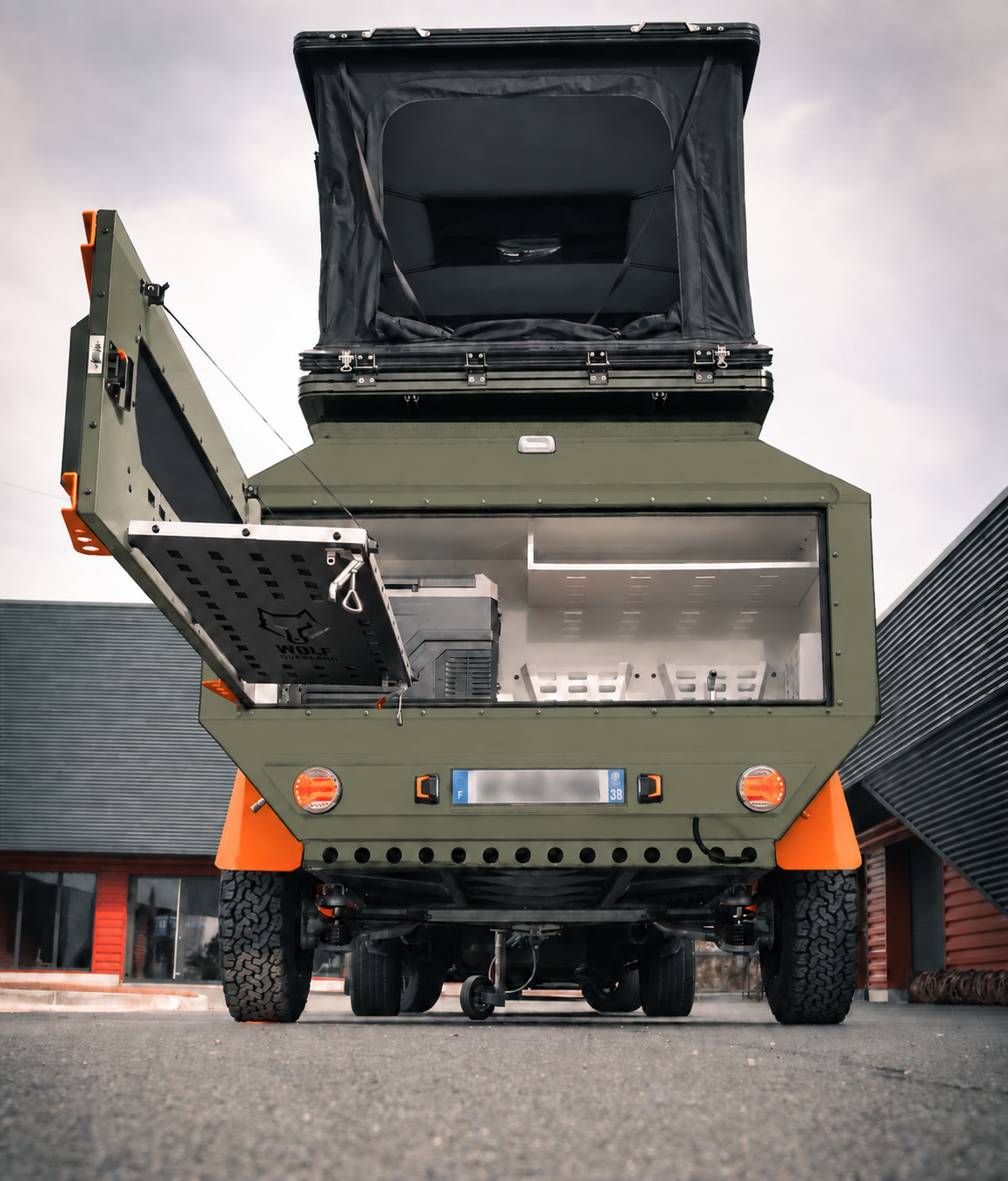Rear view of WOLF Overland caravan in tactical olive, tent raised · storage open.