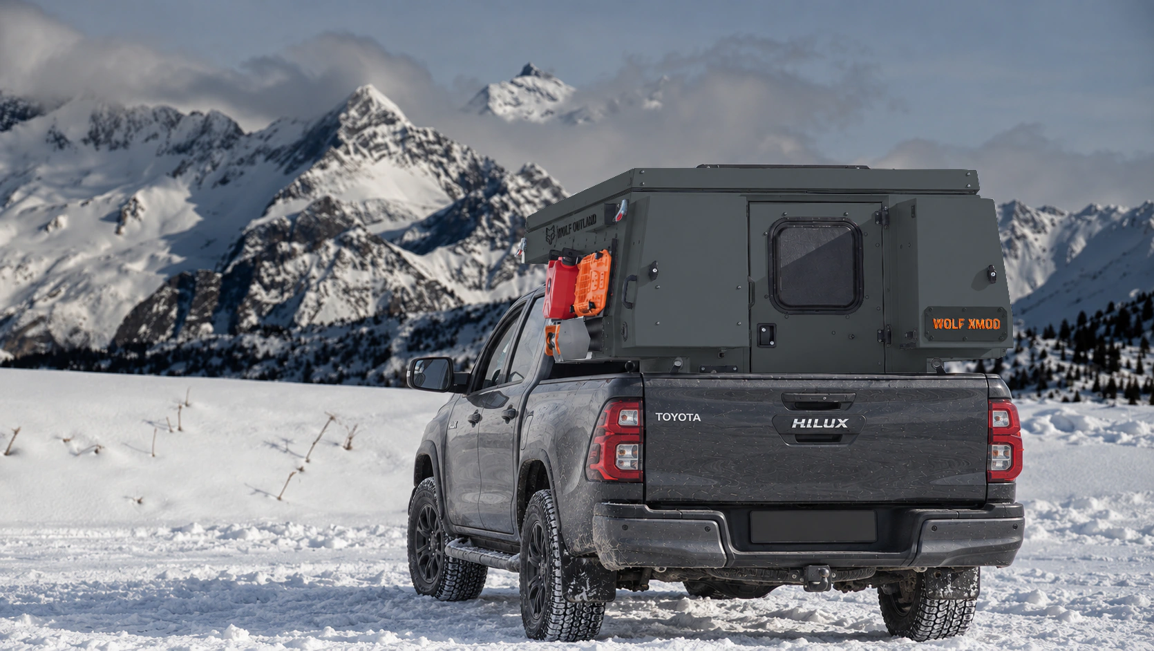 Toyota Hilux in anthracite grey with WOLF XMOD in Graphite, two solid rear cabinets — Rear view, roof closed, Orange backlit WOLF XMOD plate.