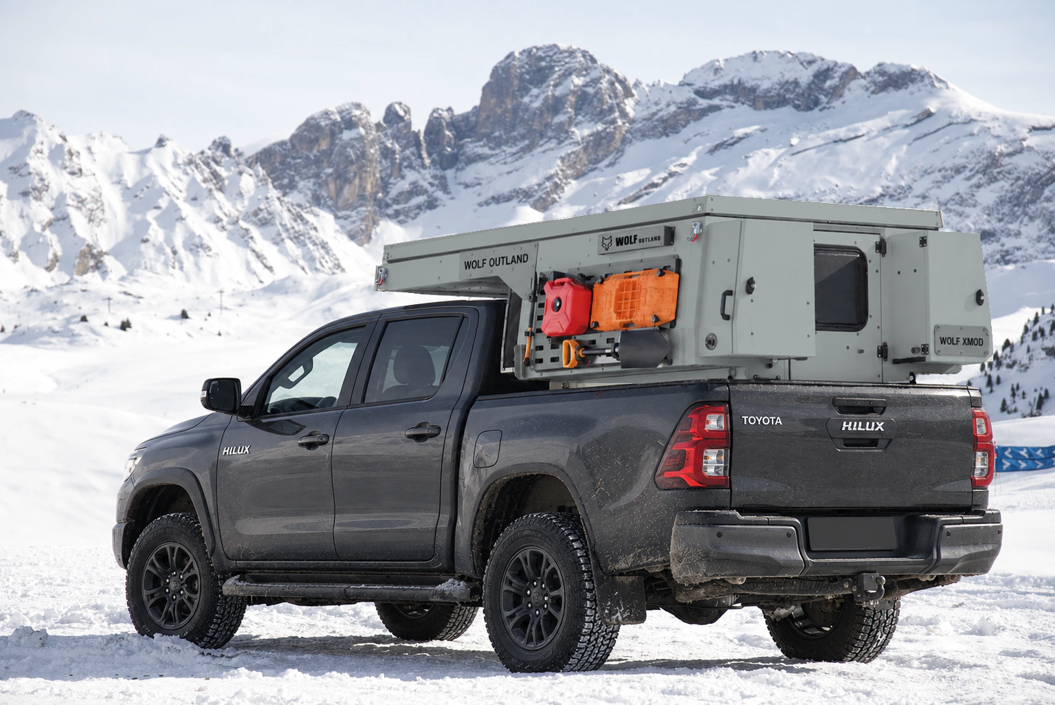 Toyota Hilux in anthracite grey with WOLF XMOD in Mineral grey, two solid rear cabinets — Rear left three-quarter view, roof closed, Black engravings.