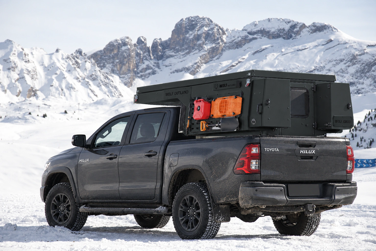 Toyota Hilux in anthracite grey with WOLF XMOD in Matt black, two solid rear cabinets — Rear left three-quarter view, roof closed, Black engravings.