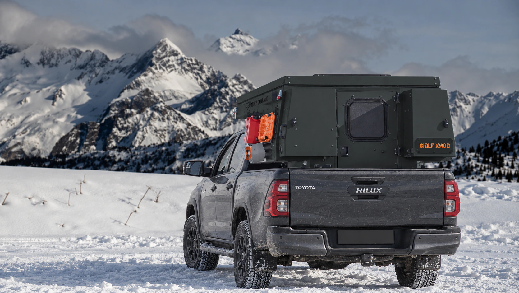 Toyota Hilux in anthracite grey with WOLF XMOD in Matt black, two solid rear cabinets — Rear view, roof closed, Orange backlit WOLF XMOD plate.