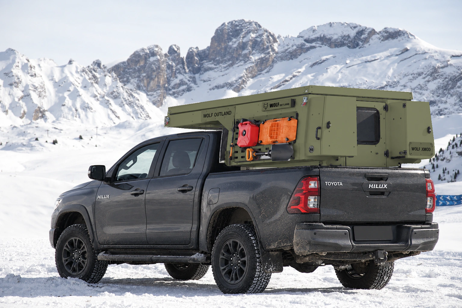 Toyota Hilux in anthracite grey with WOLF XMOD in Tactical olive, two solid rear cabinets — Rear left three-quarter view, roof closed, Black engravings.