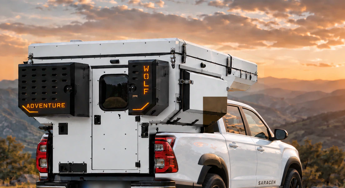 Rear close-up of a glacier white WOLF ADVENTURE pickup camper on a white KGM Musso, showing its central door, window and black storage boxes.